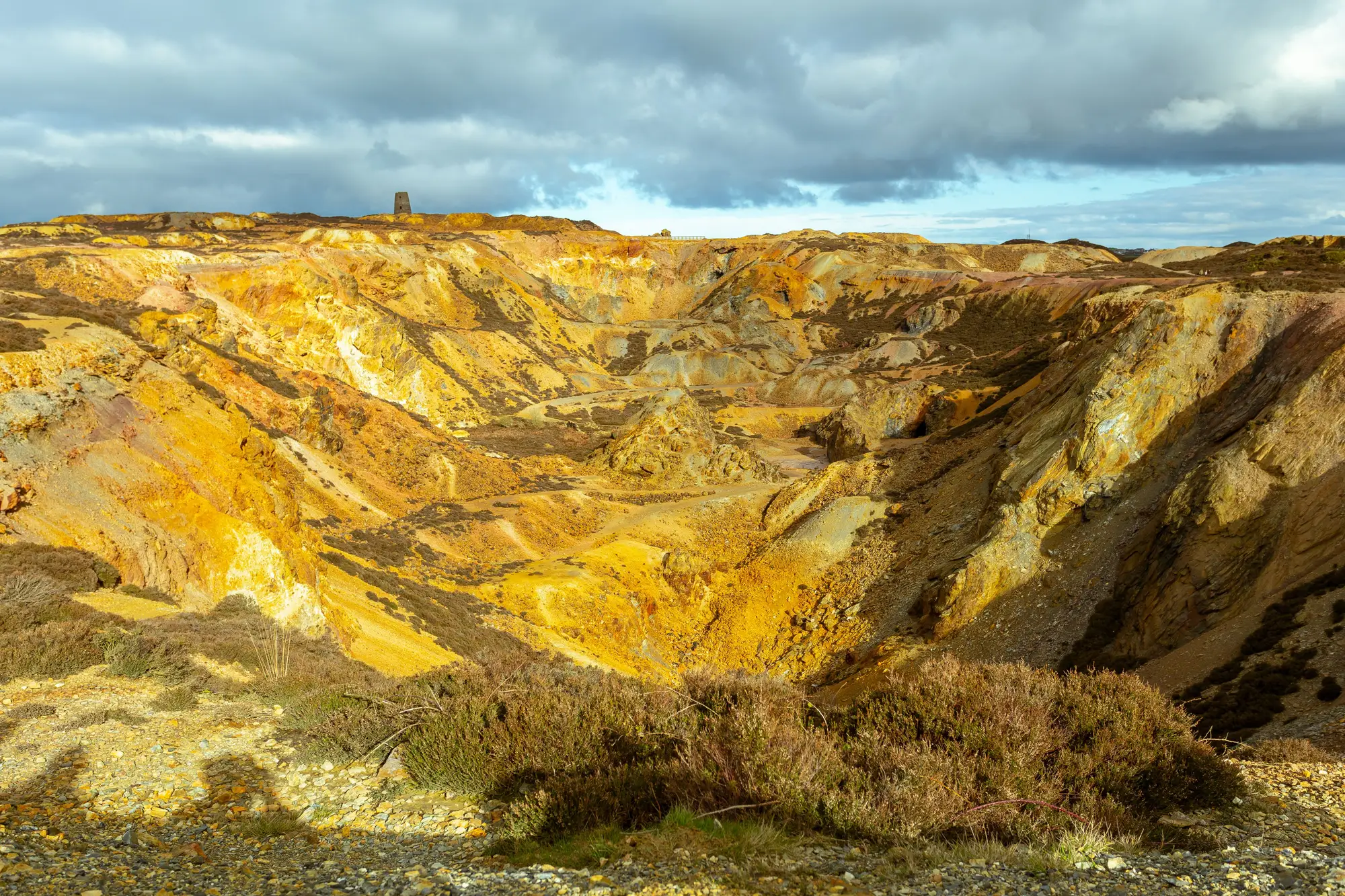 Yellow and ochre altered ground in old open workings under a heavy sky